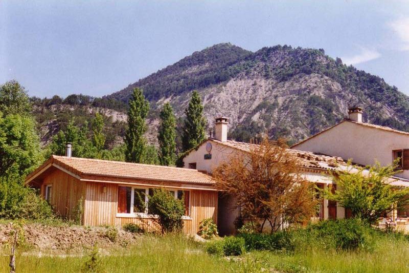 Extension en bardage bois greffée sur une maison ancienne, au pied d'une montagne
