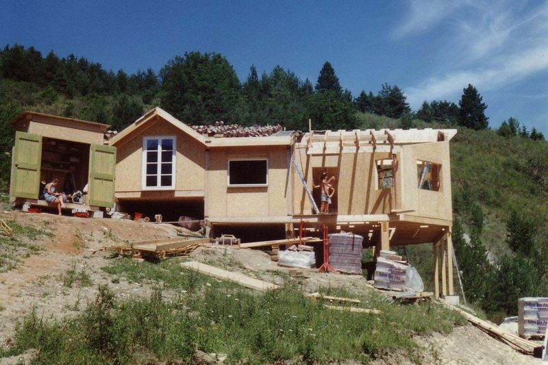 Maison à ossature bois en cours de construction sur un terrain en pente boisé