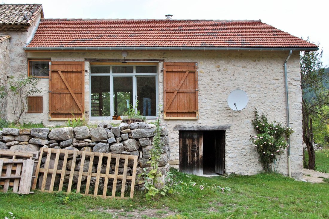 Le même bâtiment après travaux, avec une baie vitrée, des volets et une façade rejointoyée