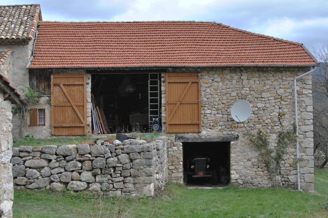 Grange en pierre avant travaux, grande ouverture de remise fermée par des volets bois