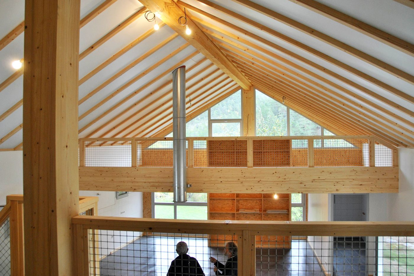 Intérieur rénové : charpente apparente, mezzanine en bois et grande baie vitrée