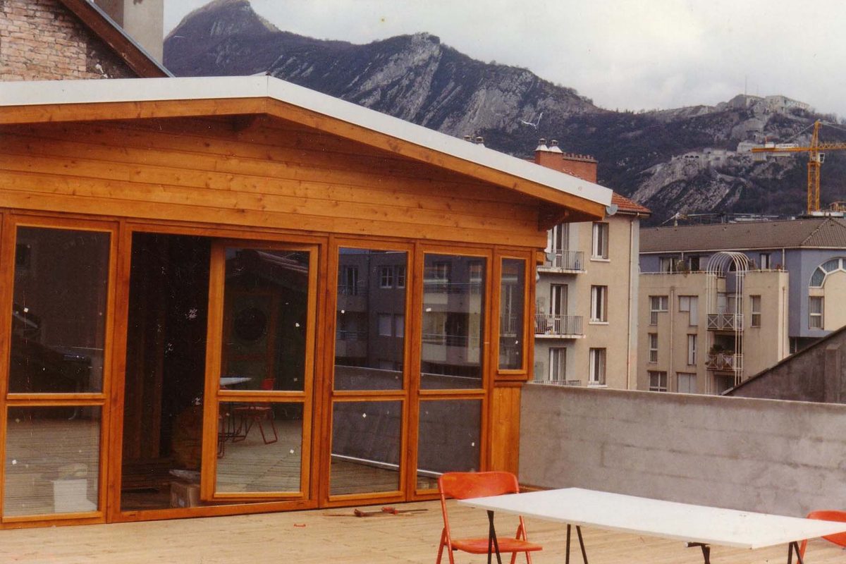 Véranda en bois et terrasse sur un toit-terrasse, montagnes en arrière-plan